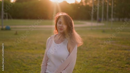 Smiling lady in unbuttoned shirt shakes loose hair on field at sunset slow motion. Enjoying warm summer evening. Freedom and active lifestyle