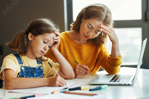Fotografie Confused mother doing homework with stressed daughter at home