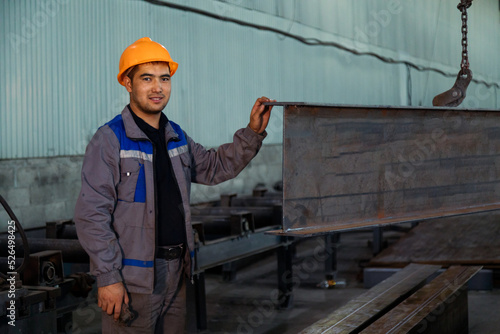 Worker receiving a metal bar from crane in warehouse © Collab Media