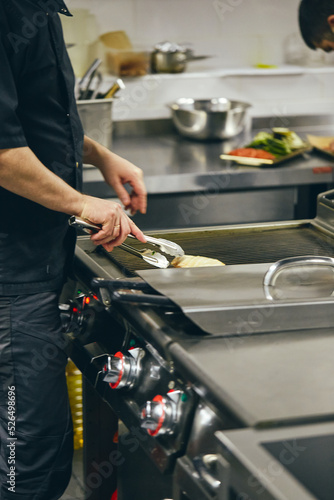 Chef in the Kitchen of the Restaurant prepares dishes for serving to guests