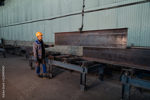 Worker receiving a metal bar from crane in warehouse © Collab Media