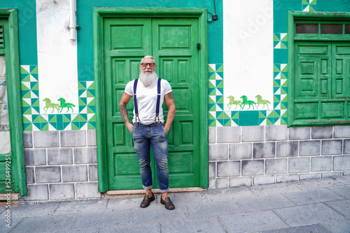 Full length photo of fashionable smiling senior man, positive emotions. Hipster guy wearing jeans and suspenders © neonshot