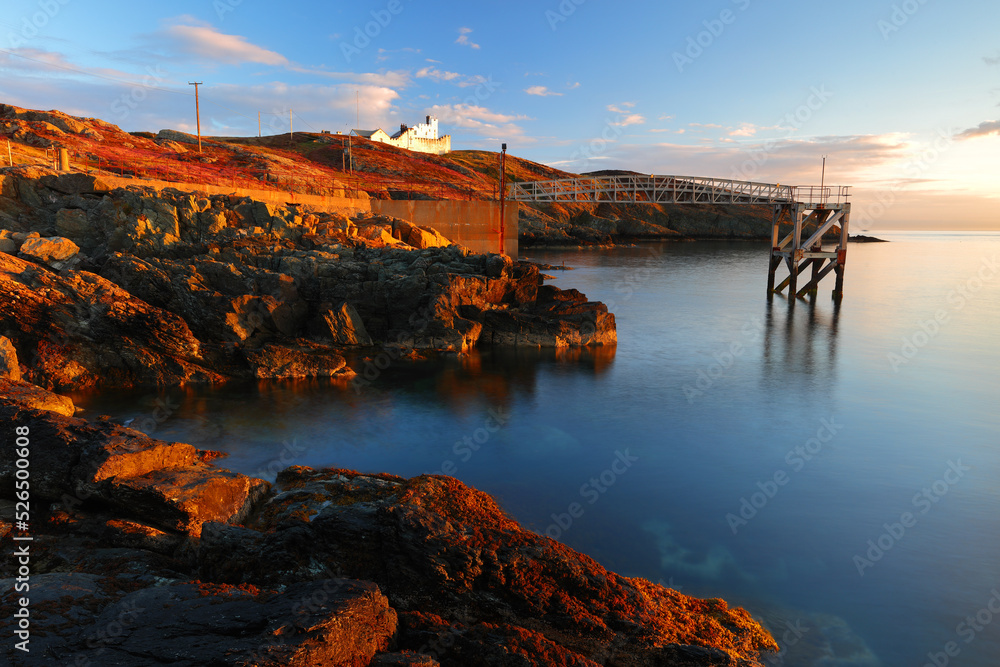 Point Lynas Lighthouse at first light with calm blue sea. Anglesey, North Wales, UK.