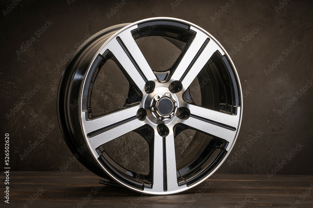 Obraz premium new black alloy wheels on a dark textured black background. wheel for car spare parts auto repair tire shop,