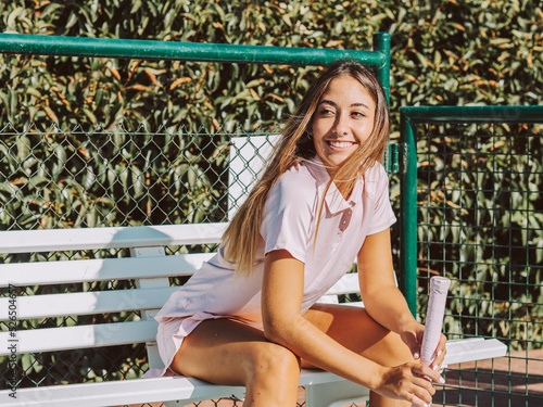 Mujer joven tenista sentada en un banco descansando  photo