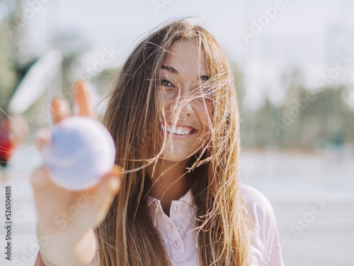 Mujer joven y guapa sujetando una pelota de tenis 