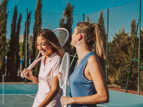 Amigas felices jugando al tenis al aire libre durante el verano photo