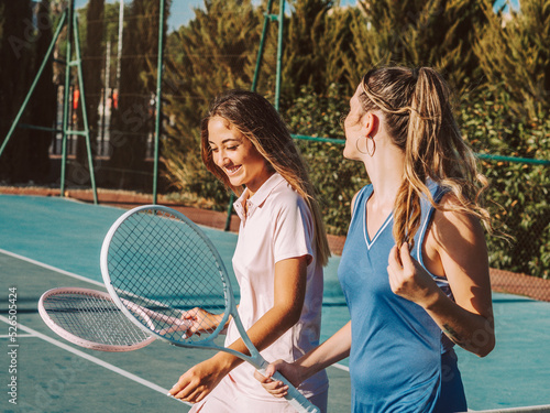 Amigas felices jugando al tenis al aire libre durante el verano
