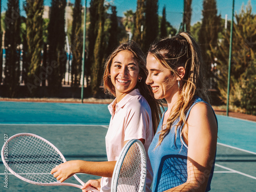 Amigas felices jugando al tenis al aire libre durante el verano