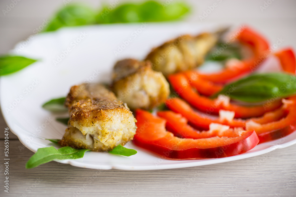 Pieces of fried hake fish in a plate with pepper Pieces of fried hake fish in a plate with pepper