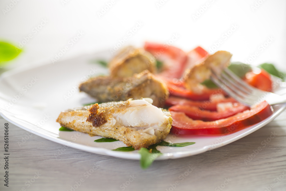 Pieces of fried hake fish in a plate with pepper