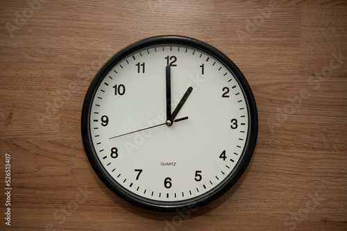 office wall clock indicating the one o clock hour
