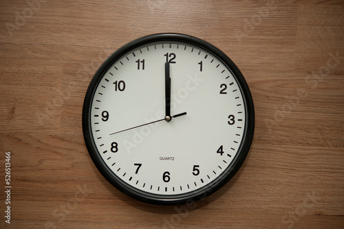 office wall clock indicating the twelve o clock hour