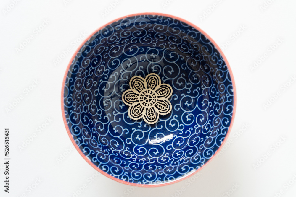 wooden ornament at the bottom of a blue bowl with curly pattern