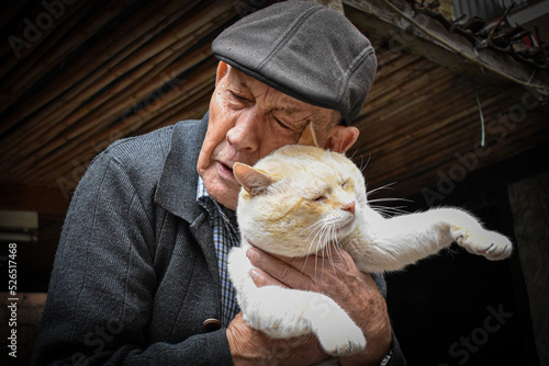 Hombre mayor con gorra abrazando a su gato blanco photo