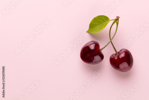 Cherry berries on a pastel background top view. Background with a cherry on a sprig, flat lay