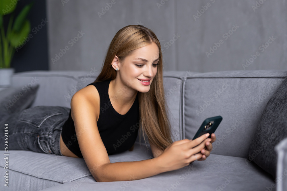 Portrait beautiful young woman use smart mobile phone on sofa in living room interior Portrait beautiful young woman use smart mobile phone on sofa in living room interior