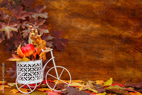 souvenir decorative white bicycle with a pumpkin and autumn leaves on a wooden background. Autumn postcard. Copy space, place for text