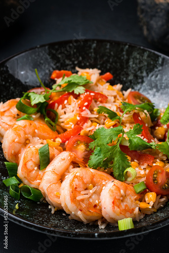 Quick and healthy Asian meal made of fried rice, fresh shrimps and vegetables in a black bowl