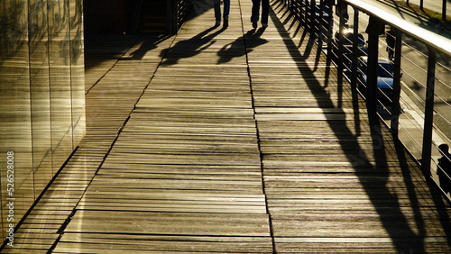 Two shadows of people on a wooden sunny surface
