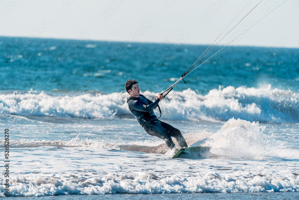 young latino practicing kitesurfing in the pacific ocean