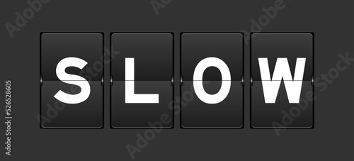 Black color analog flip board with word slow on gray background