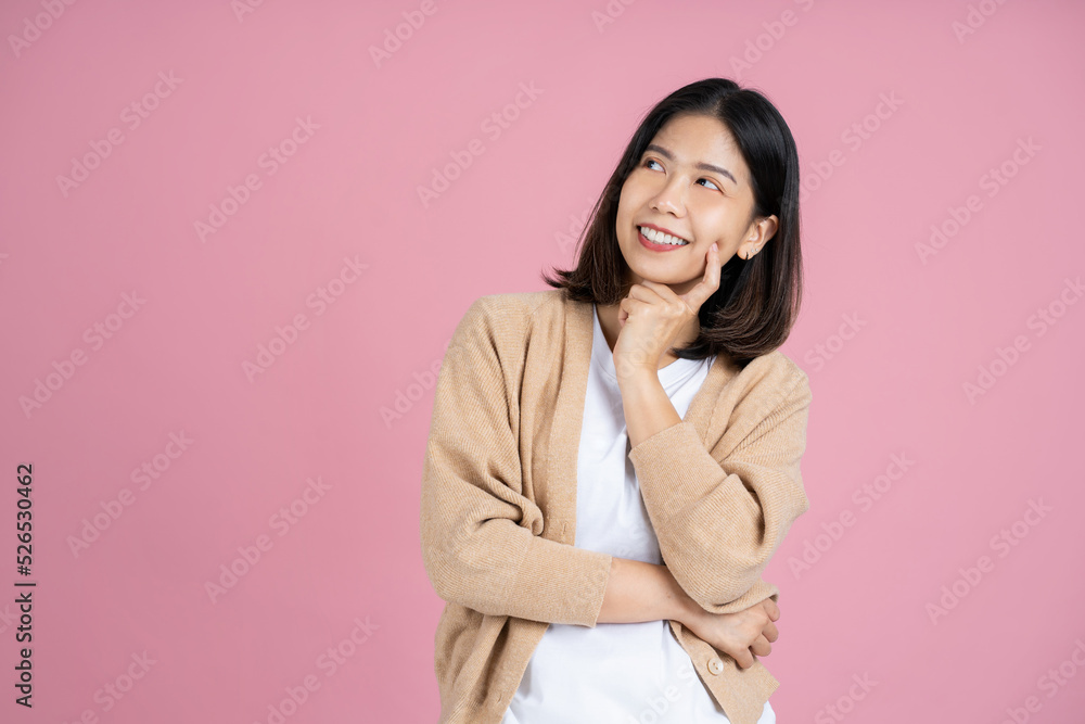 Asian woman thinking something and standing on pink background. Isolated. Asian woman thinking something and standing on pink background. Isolated.