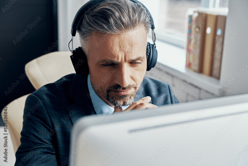 Close-up of businessman in headphones having web conference while sitting at his working place Close-up of businessman in headphones having web conference while sitting at his working place