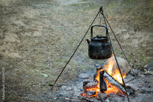 Campfire with cooking food in a saucepan on a tripod. Cooking on fire, camping cooking. Living in tents in the fresh air. Campfire at the campsite. Camping food, cooking on an open fire. Copy space