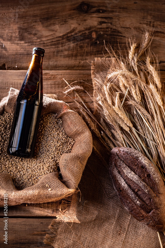Dark beer in a bottle. Beer and ears of wheat. Dark bread and wheat.