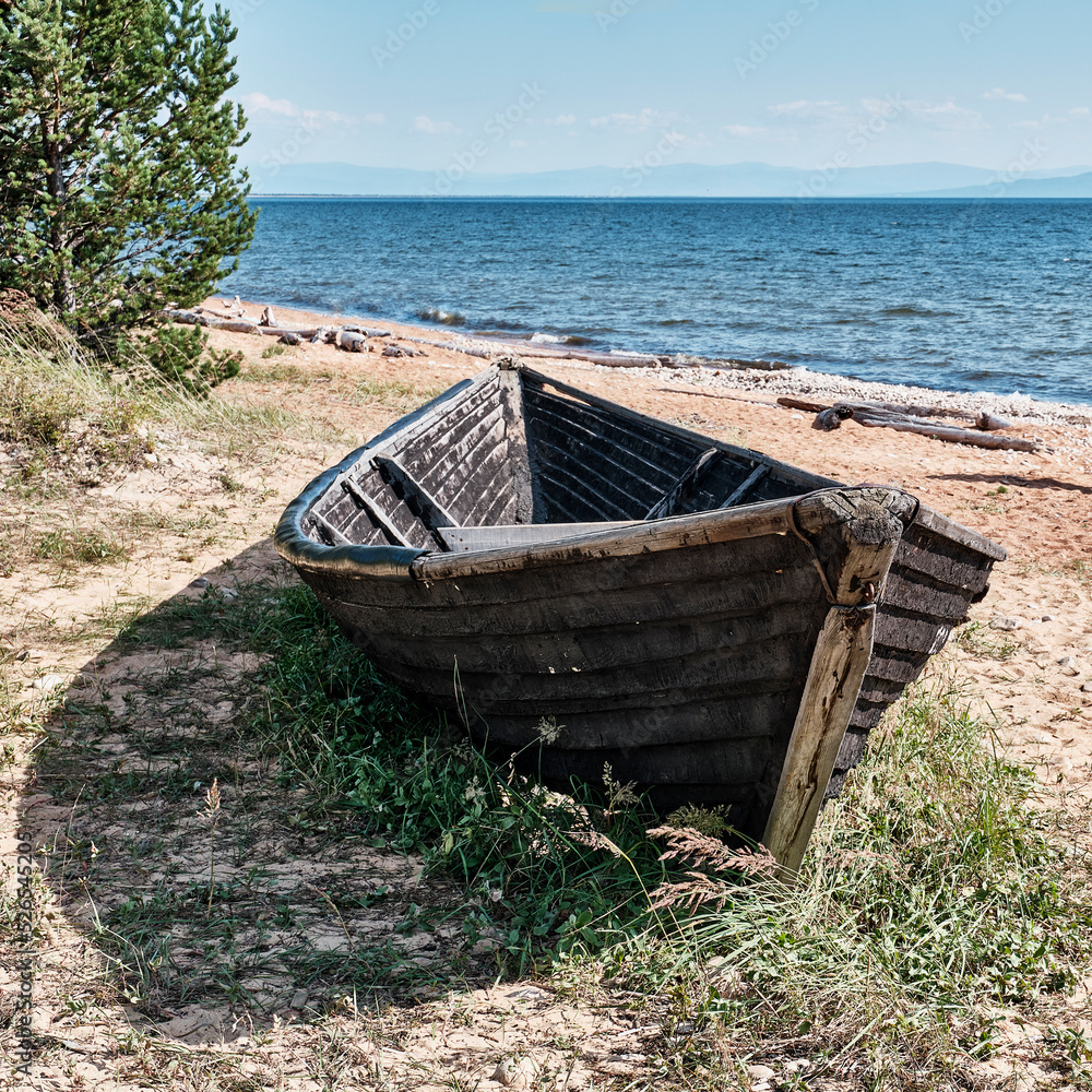 Old fishing wooden longboat on shore of Kultuk Bay. Lake Baikal, Zabaikalsky National Park, Russia.