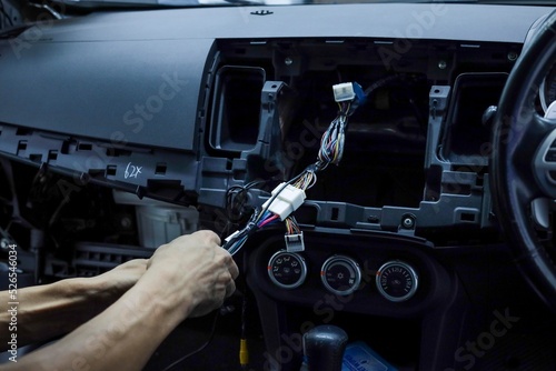 Cropped hand fixing cables of a car dashboard. Noise and luminance are visible due to low light and high ISO