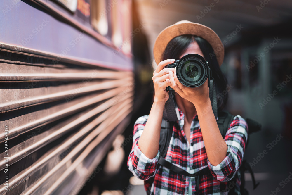 Φωτογραφία Tourist woman taking a photo with camera of side of train on railway background