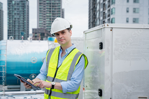 An engineer's portrait is examining the cooling tower air conditioner of a huge industrial building to control airflow.