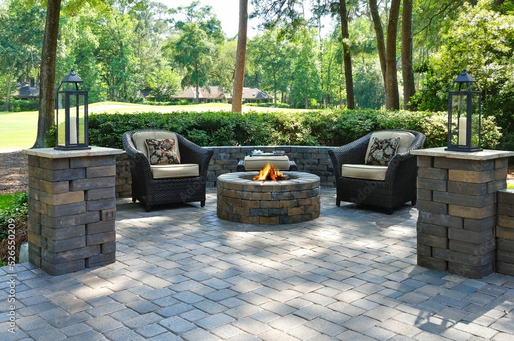 Beautiful outdoors pavers with two comfortable armchairs and a fire pit in a green environment - obrazy, fototapety, plakaty 