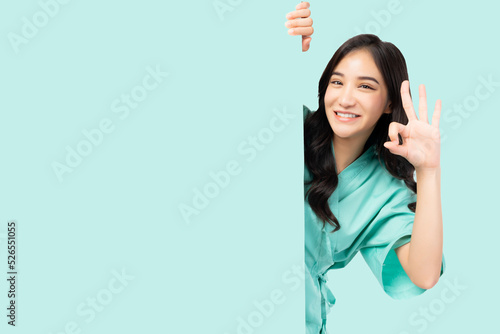 Fotografija Happy patient woman okay hand sign hiding behind green wall with blank space iso