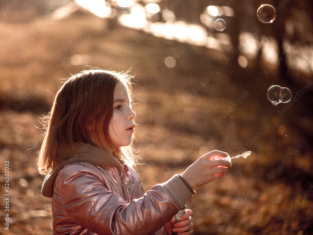 cute girl on a walk blows soap bubbles