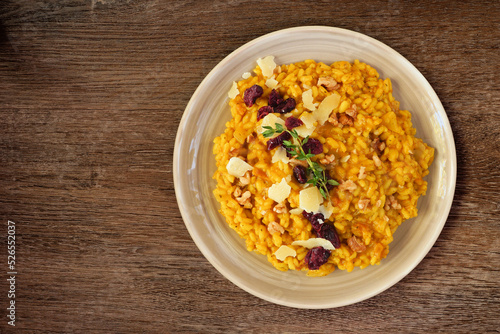 Autumn pumpkin risotto with cranberries and parmesan cheese. Top down view on a rustic wood background.