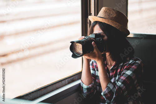 Tourist woman taking a photo with camera of side of train on railway background. Young asian woman traveler with backpack in the railway, Travel concept