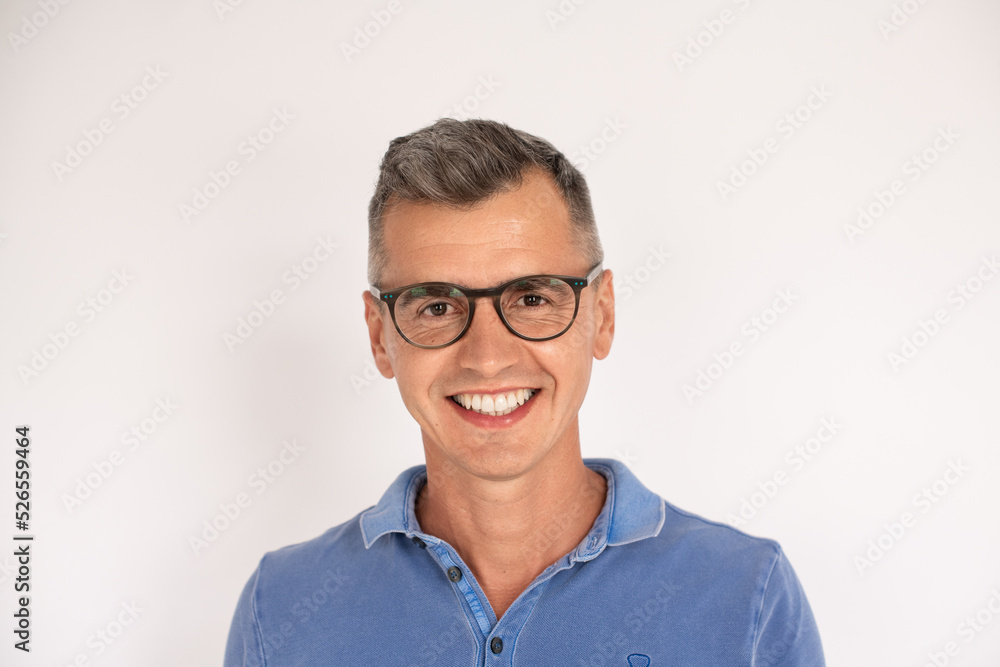 Portrait of happy mature man wearing blue t-shirt and glasses. Caucasian man wearing blue T-shirt standing over white background. Eyesight concept Portrait of happy mature man wearing blue t-shirt and glasses. Caucasian man wearing blue T-shirt standing over white background. Eyesight concept