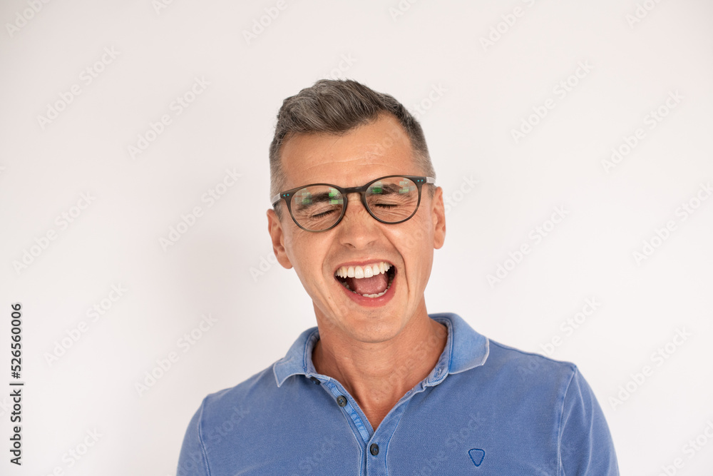 Portrait of funny mature man wearing glasses yawning. Caucasian man wearing blue T-shirt standing with open mouth over white background. Making faces concept