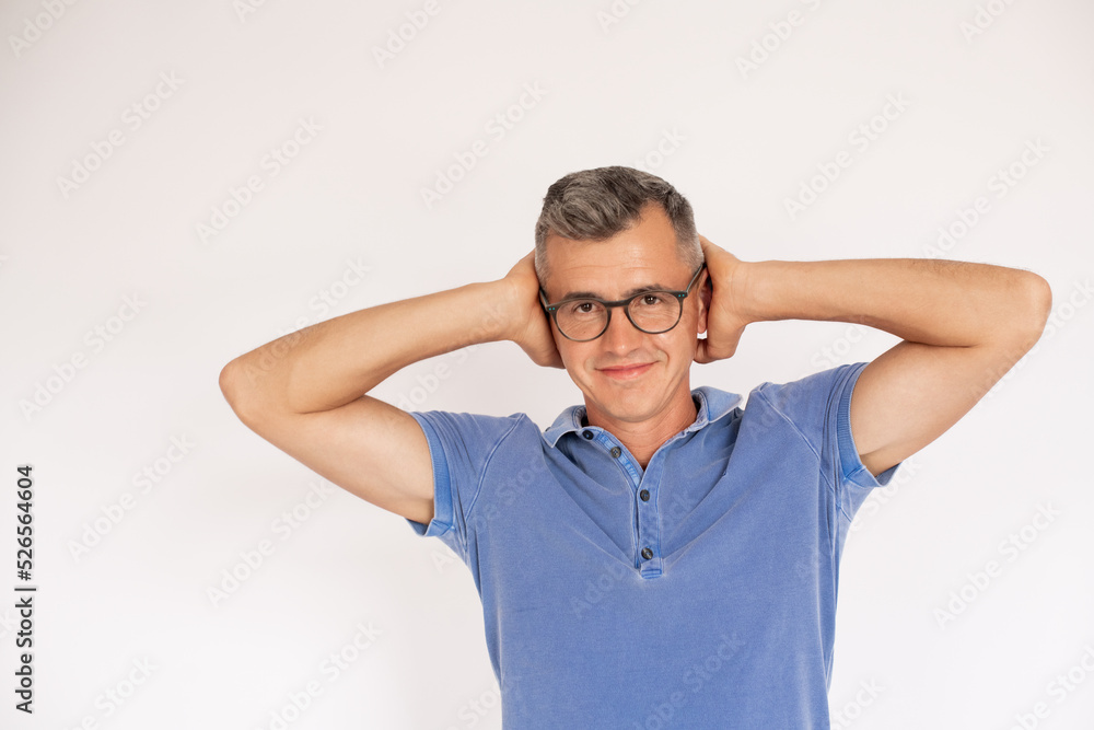 Portrait of happy mature man wearing glasses covering ears. Caucasian man wearing blue T-shirt looking at camera and smiling against white background. Noise concept Portrait of happy mature man wearing glasses covering ears. Caucasian man wearing blue T-shirt looking at camera and smiling against white background. Noise concept