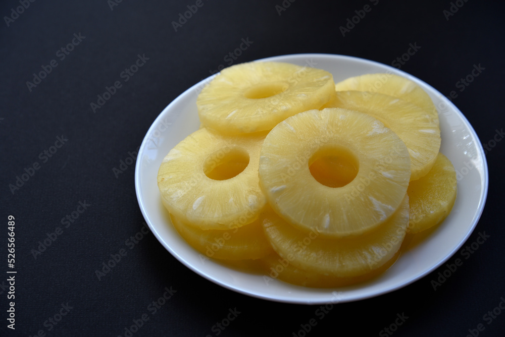 Delicious fresh pineapple rings on a plate on a black background. Delicious breakfast of pineapple rings. Delicious fresh pineapple rings on a plate on a black background. Delicious breakfast of pineapple rings.