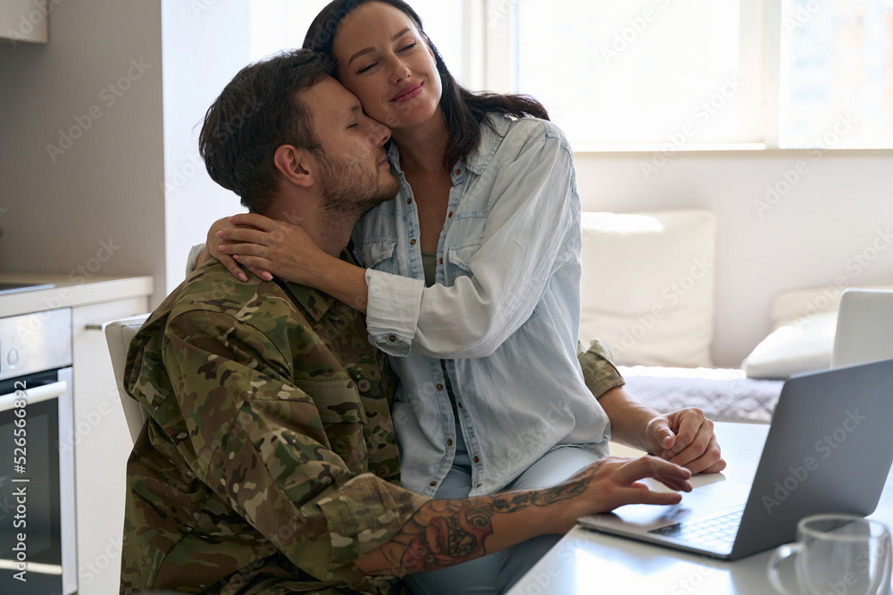 Young woman gently hugging a soldier in military uniform Young woman gently hugging a soldier in military uniform