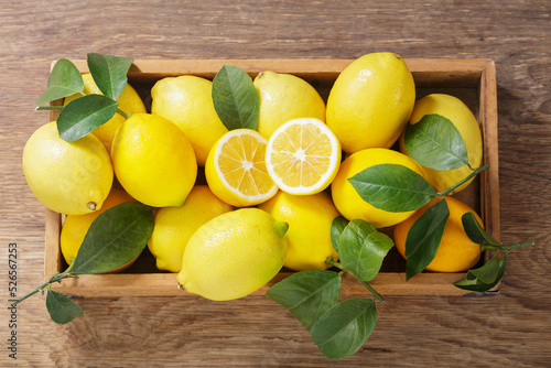 wooden box of fresh lemons with leaves, top view