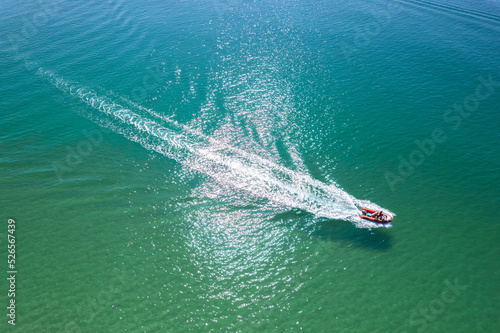 Boat moving at high speed on the sea. A long Wake follows the boat. Blurred movement. Shooting from a drone..