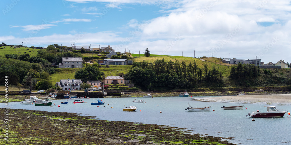 Clonakilty, Ireland, July 2, 2022. The sunny coast of Ireland. Small fishing boats are anchored in Clonakilty Bay at low tide. Picturesque seascape. European fishing village on the shore.