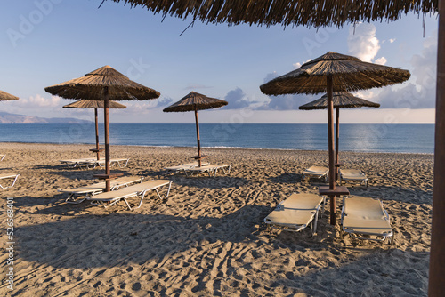 Empty beach with sun loungers and umbrellas in the early morning on a sunny day on the Crete island Greece. . High quality photo