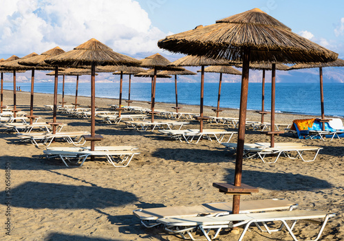 Empty beach with sun loungers and umbrellas in the early morning on a sunny day on the Crete island Greece. . High quality photo