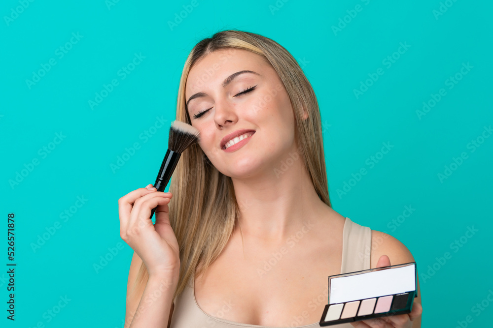 Young caucasian woman isolated on blue background with makeup palette and happy Young caucasian woman isolated on blue background with makeup palette and happy